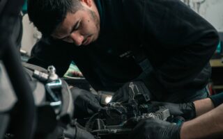 A mechanic installs some auto parts into a car